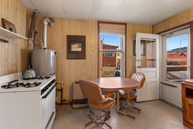 kitchen with white range with gas cooktop, a healthy amount of sunlight, and wood walls