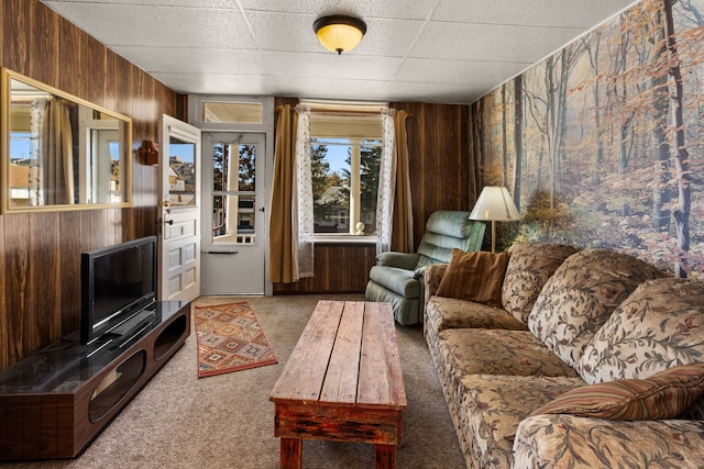 living room with a drop ceiling, carpet floors, and wooden walls