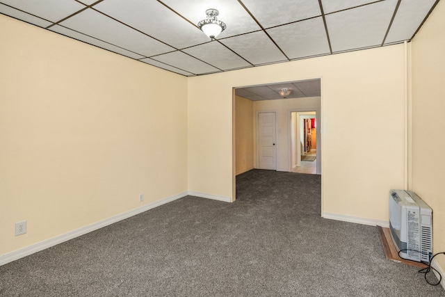 unfurnished room featuring a paneled ceiling and dark carpet