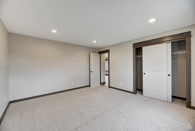 unfurnished bedroom featuring light colored carpet and a closet