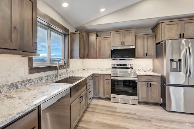 kitchen with sink, tasteful backsplash, light hardwood / wood-style flooring, vaulted ceiling, and appliances with stainless steel finishes