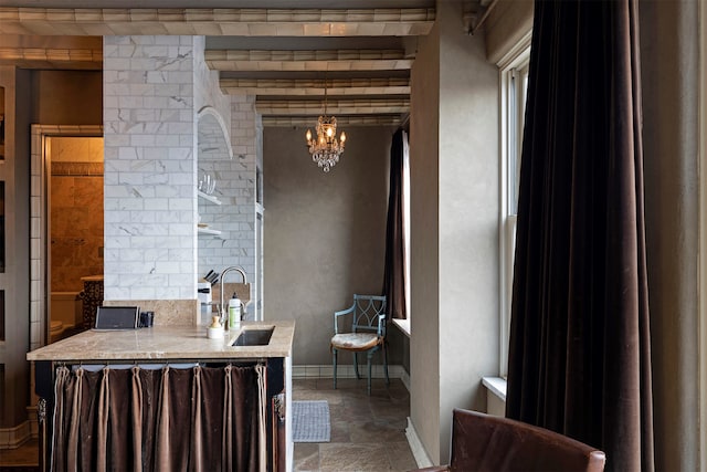 bathroom with a notable chandelier, beam ceiling, and sink