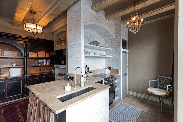 kitchen featuring pendant lighting, a center island with sink, beam ceiling, stainless steel appliances, and a chandelier