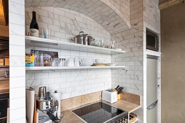 kitchen with refrigerator, decorative backsplash, stainless steel microwave, and black range oven