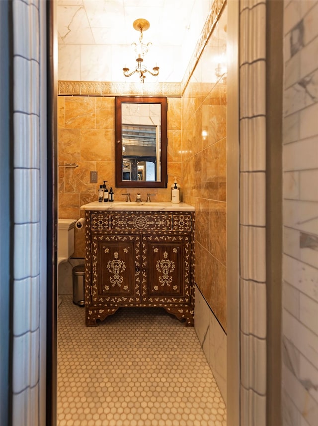 bathroom with vanity, toilet, and tile walls