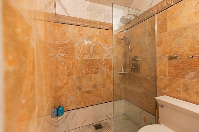 bathroom featuring tiled shower and toilet