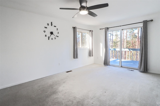 spare room with carpet floors, a ceiling fan, visible vents, and baseboards