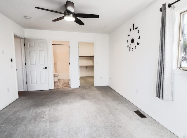 unfurnished bedroom with ceiling fan, connected bathroom, carpet floors, visible vents, and a spacious closet