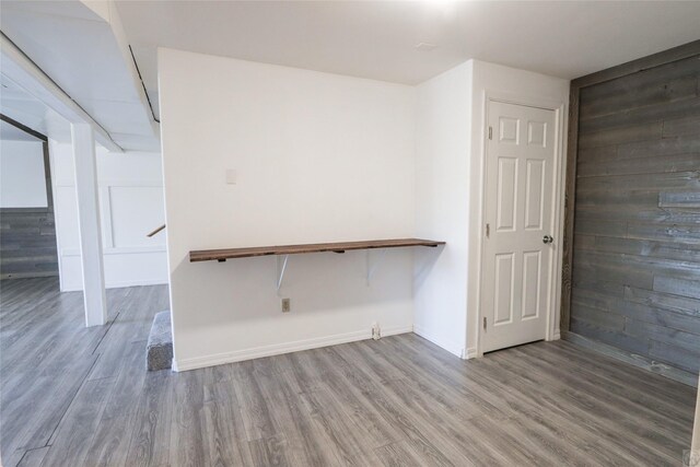 empty room with baseboards, wood finished floors, and wooden walls