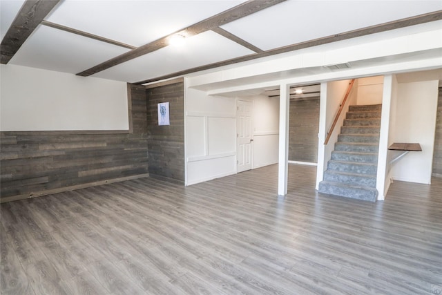 finished below grade area featuring a wainscoted wall, stairs, visible vents, and wood finished floors