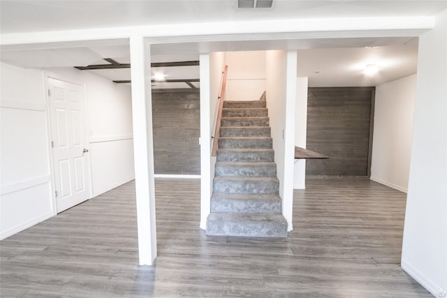 staircase featuring visible vents, wood finished floors, and beamed ceiling