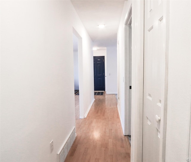 hallway featuring light wood-type flooring, visible vents, and baseboards