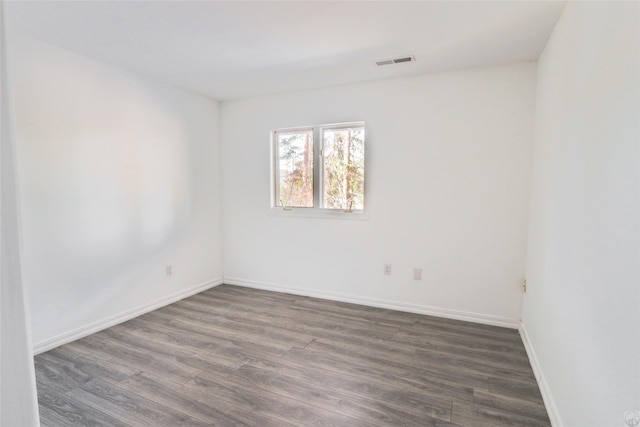 unfurnished room featuring dark wood-style floors, baseboards, and visible vents