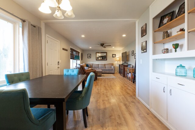 dining area with light hardwood / wood-style floors and ceiling fan with notable chandelier