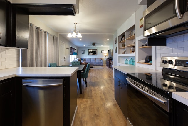 kitchen featuring ceiling fan with notable chandelier, backsplash, hanging light fixtures, stainless steel appliances, and light wood-type flooring