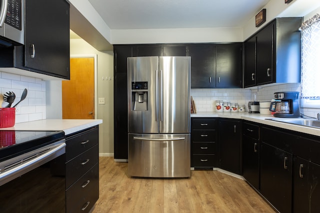 kitchen featuring decorative backsplash, stainless steel appliances, sink, and light hardwood / wood-style flooring