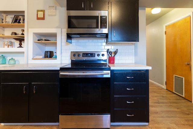 kitchen with backsplash, light hardwood / wood-style flooring, and appliances with stainless steel finishes