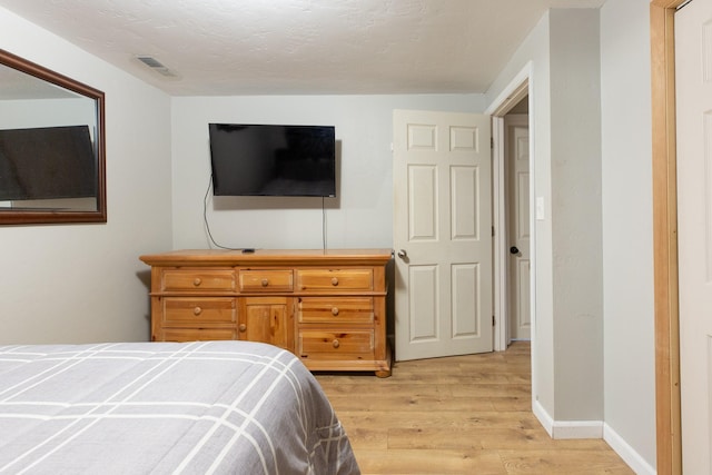 bedroom with light hardwood / wood-style flooring and a textured ceiling