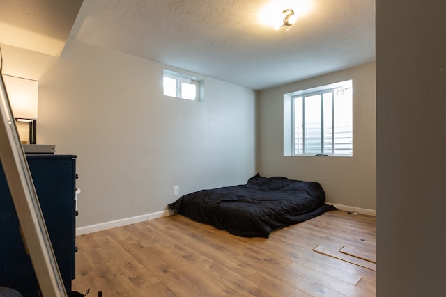 bedroom featuring a textured ceiling, light hardwood / wood-style flooring, and multiple windows