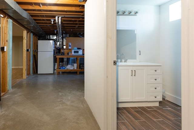 basement with dark hardwood / wood-style flooring, sink, and white fridge