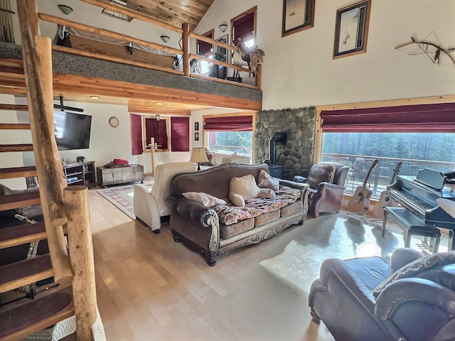 living room featuring hardwood / wood-style floors, a wood stove, and high vaulted ceiling