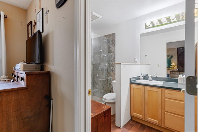 bathroom with toilet, vanity, an enclosed shower, and hardwood / wood-style flooring