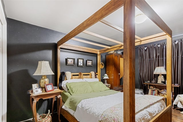 bedroom featuring beam ceiling and hardwood / wood-style floors