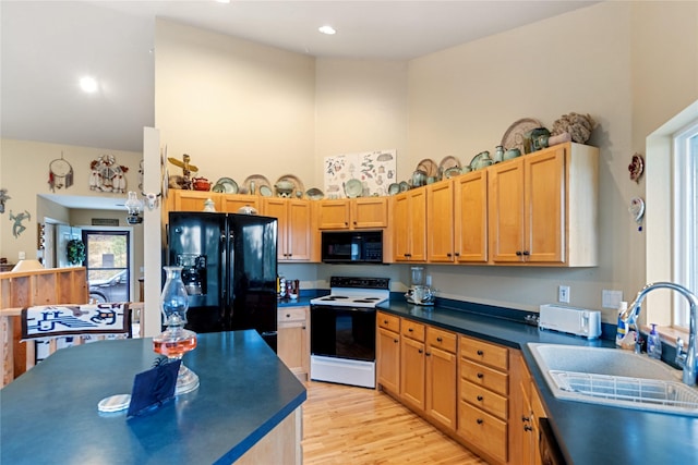 kitchen featuring black appliances, light wood-type flooring, sink, and a high ceiling