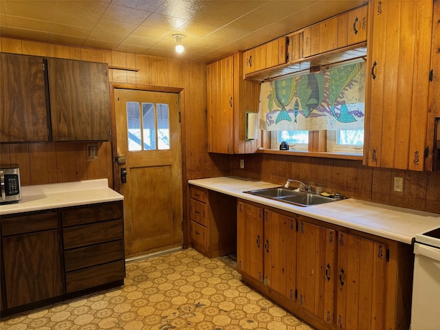 kitchen featuring electric stove, wooden walls, and sink