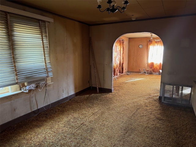 carpeted spare room with an inviting chandelier and ornamental molding