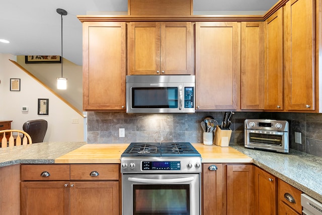 kitchen with backsplash, appliances with stainless steel finishes, and pendant lighting