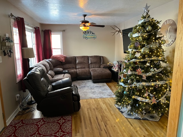 living room featuring hardwood / wood-style flooring, ceiling fan, and a textured ceiling