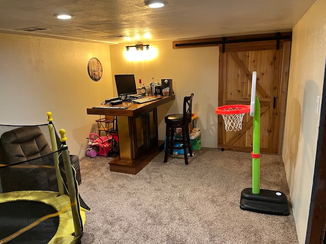 carpeted office featuring a barn door and a textured ceiling