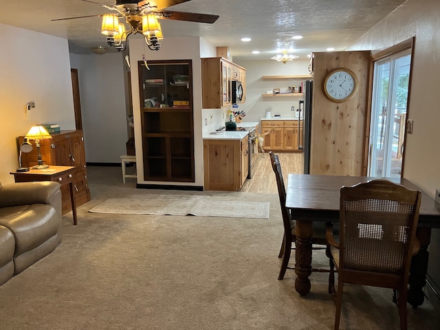 dining room featuring ceiling fan, light colored carpet, and a textured ceiling