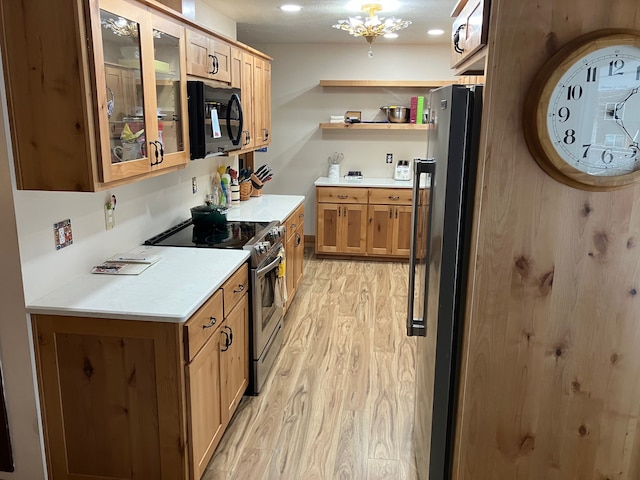 kitchen with stainless steel appliances, an inviting chandelier, and light hardwood / wood-style floors