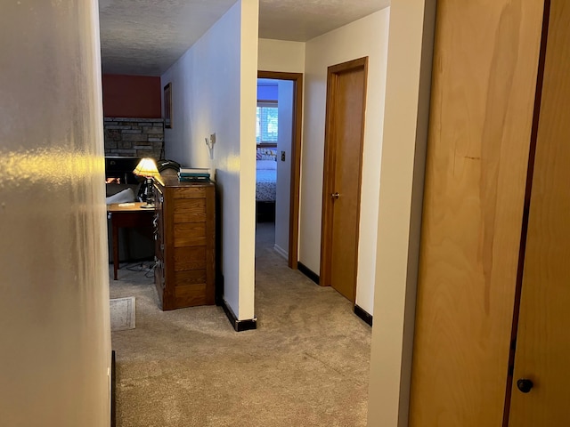 corridor featuring light colored carpet and a textured ceiling