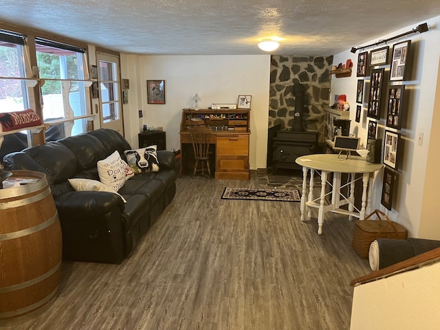 living room with a wood stove, a textured ceiling, and hardwood / wood-style flooring