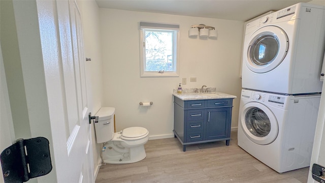 washroom with light hardwood / wood-style flooring, stacked washer and clothes dryer, and sink