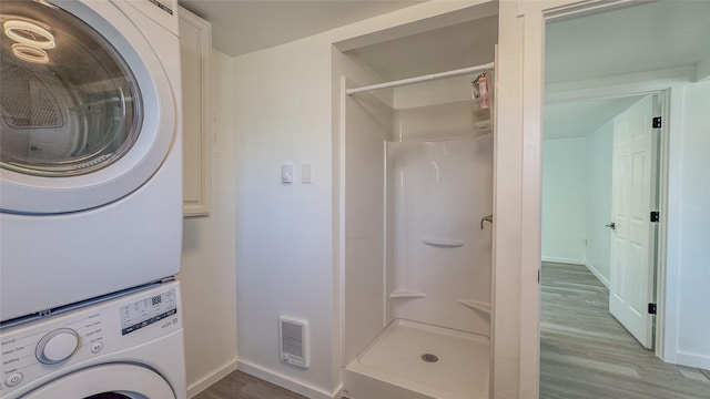 laundry area featuring wood-type flooring and stacked washer and clothes dryer