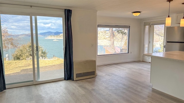 unfurnished dining area featuring heating unit, a water and mountain view, and wood-type flooring