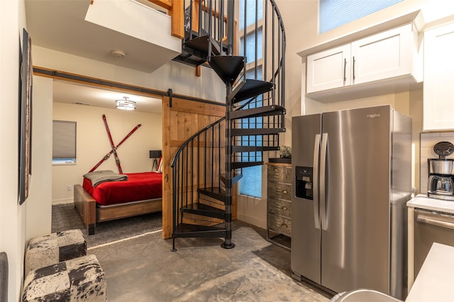 interior space featuring white cabinetry, a barn door, and stainless steel fridge with ice dispenser