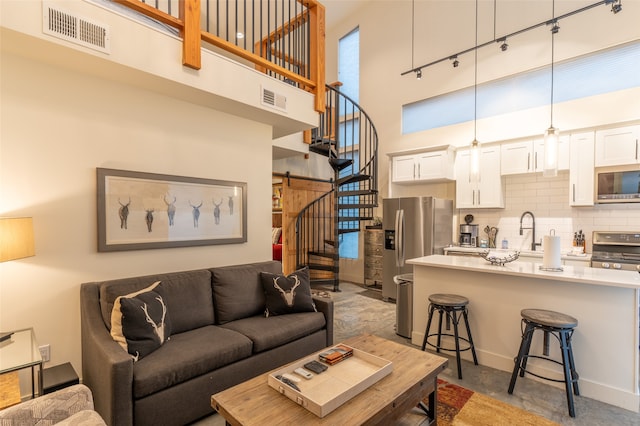 living room with a barn door, a towering ceiling, and sink