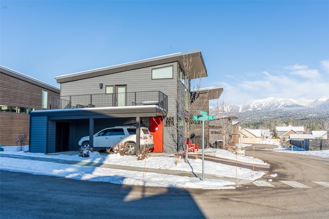 view of front facade featuring a mountain view, a balcony, and a carport