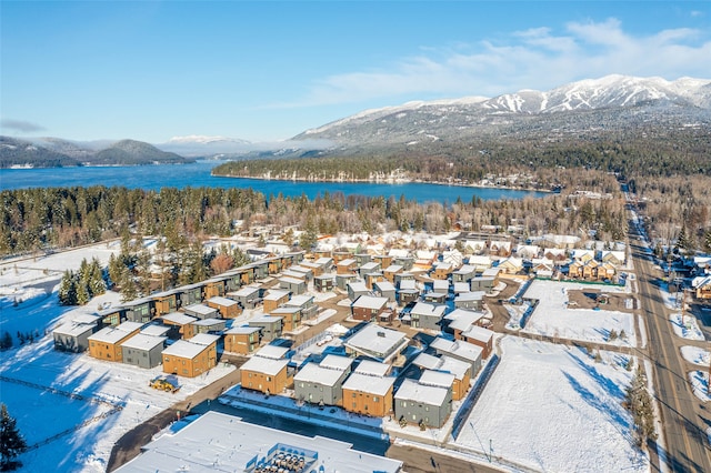 snowy aerial view featuring a water and mountain view