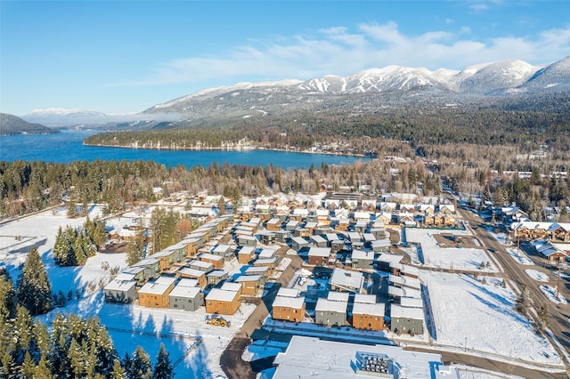 snowy aerial view featuring a water and mountain view