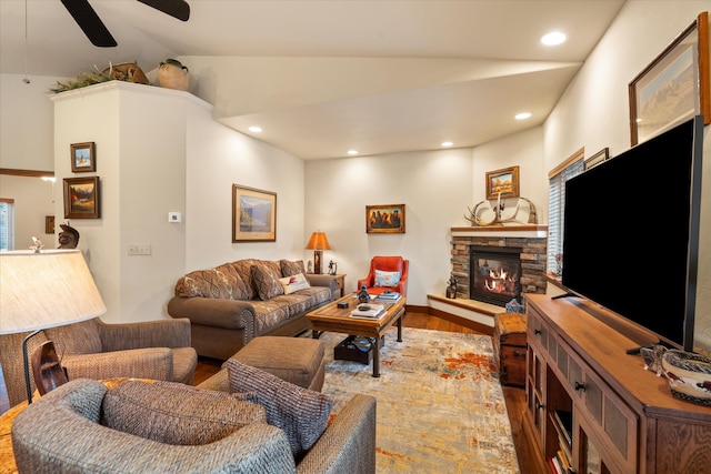 living room with a fireplace, vaulted ceiling, ceiling fan, and dark wood-type flooring