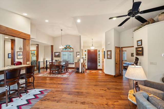 living room with ceiling fan with notable chandelier, dark hardwood / wood-style floors, and high vaulted ceiling