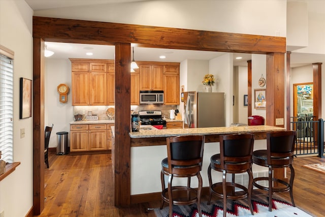 kitchen featuring backsplash, light hardwood / wood-style flooring, a breakfast bar area, and appliances with stainless steel finishes