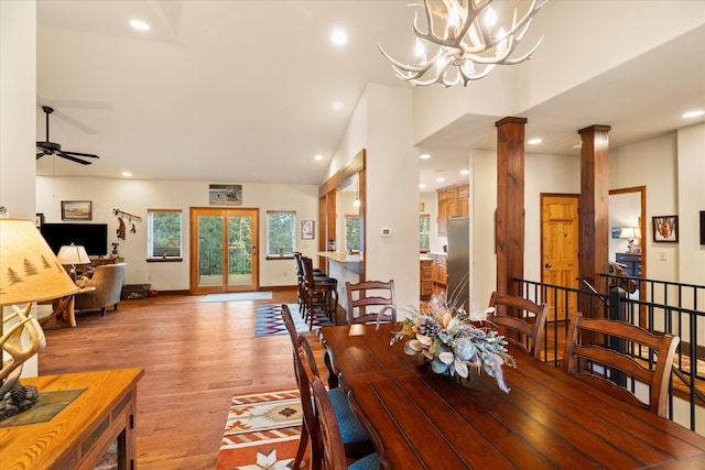 dining space featuring vaulted ceiling, ornate columns, light hardwood / wood-style flooring, and ceiling fan with notable chandelier