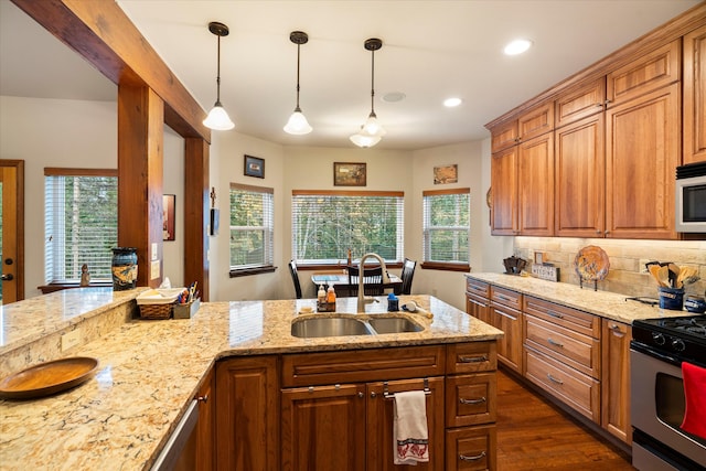 kitchen featuring sink, light stone counters, dark hardwood / wood-style floors, pendant lighting, and stainless steel range with gas stovetop